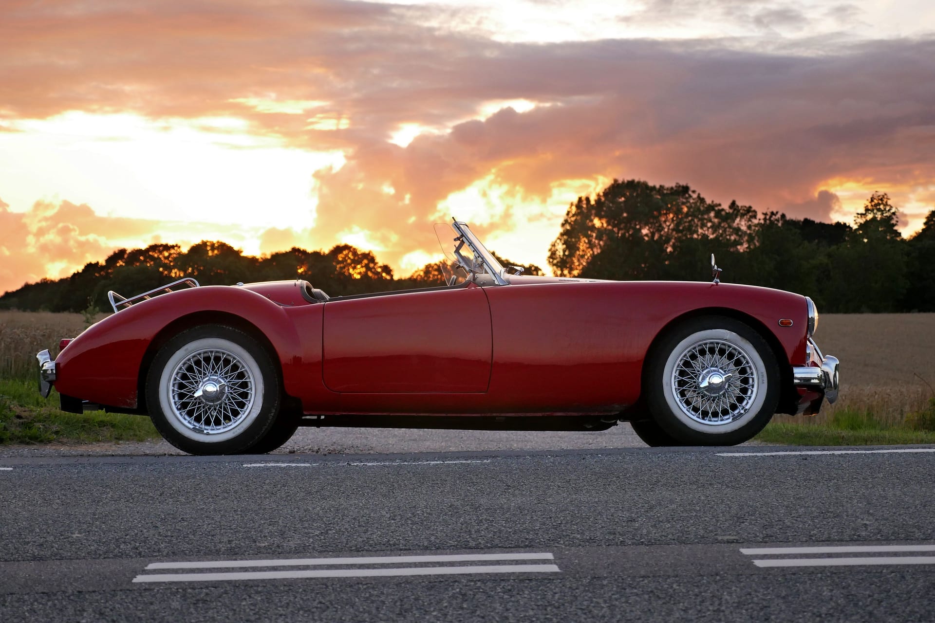 Roter Oldtimer-Roadster am Feldrand bei Sonnenuntergang